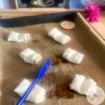 Zugeschnittene Blätterteigstücke auf Backblech, Franzbrötchenform in Bearbeitung mit Teigschaber